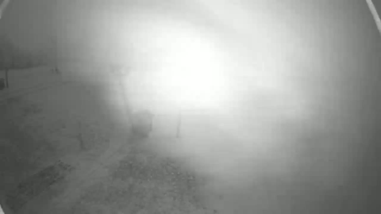 A blurry, low-light outdoor image shows a foggy or misty scene with indistinct ground features.