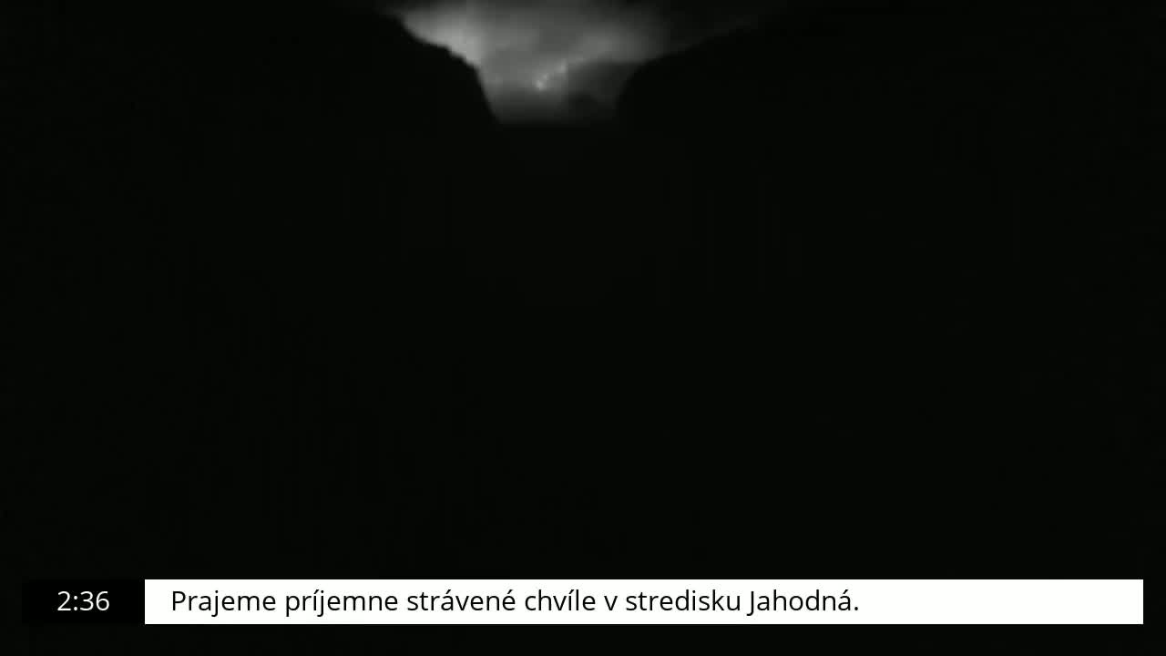 A nighttime, dark scene shows a bright, cloudy area in the distance.