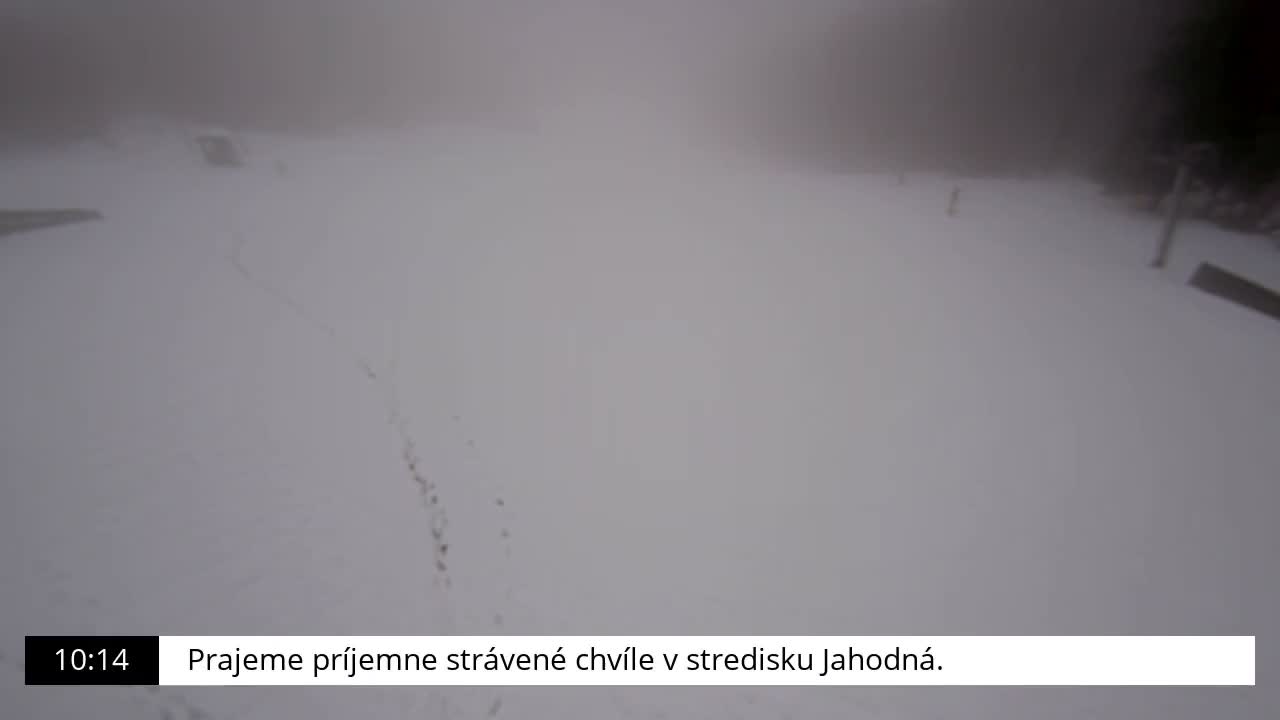 A snow-covered outdoor landscape, possibly a ski slope, is visible under very foggy or heavily overcast conditions with poor visibility.