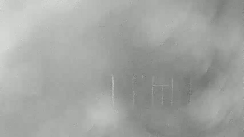A blurry, hazy image shows a few faintly visible vertical lines, possibly part of a structure, in the middle-ground.