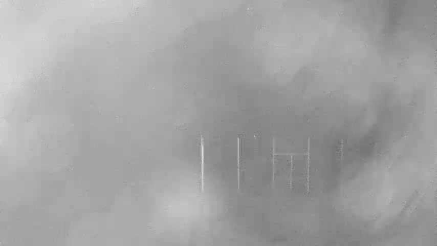 A blurry, hazy image shows faintly visible vertical lines, possibly a fence or bars, in the distance on a foggy day.