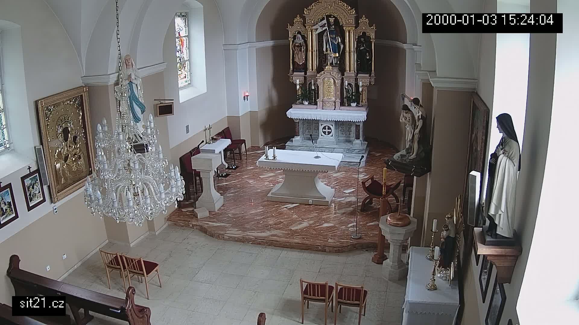An overhead view of the interior of a church, showing an altar, several religious statues, a large crystal chandelier, and a marble floor.