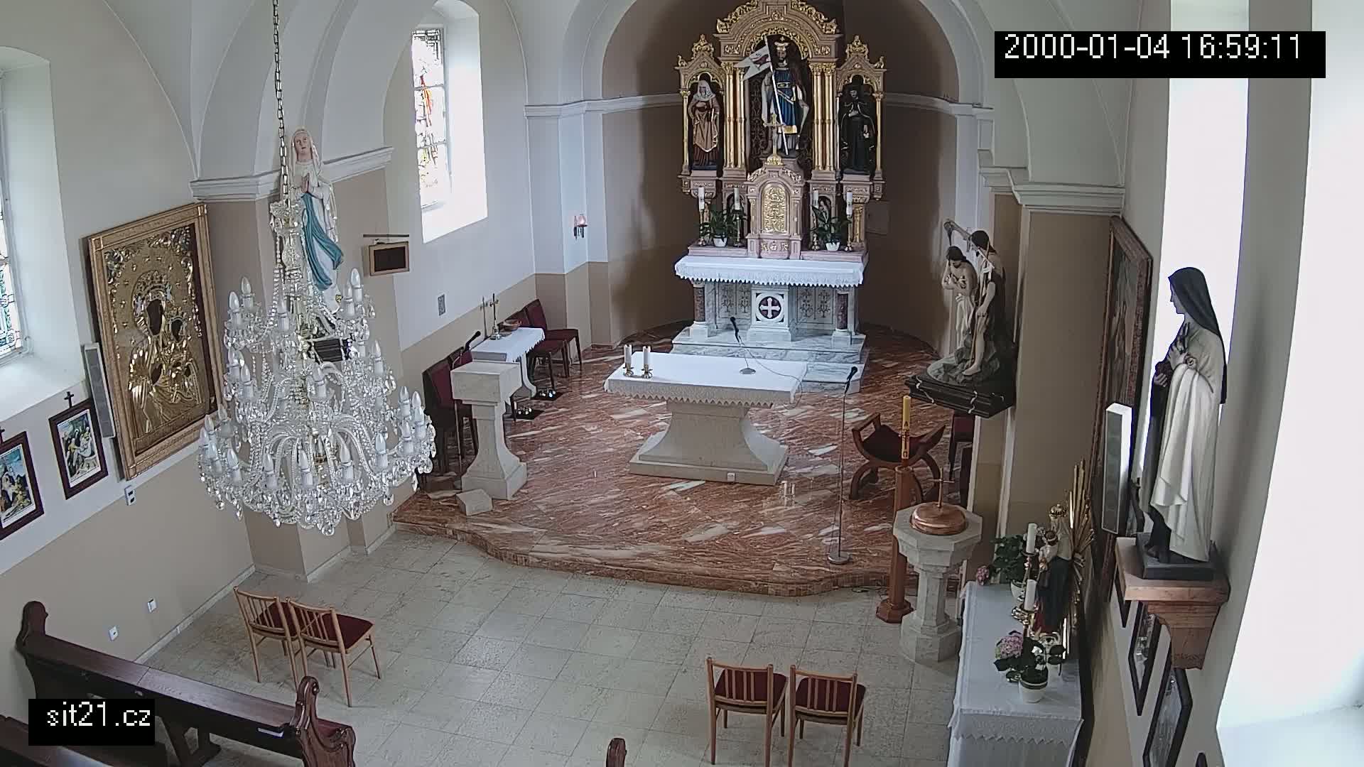 A church interior with marble floors, an altar, several religious statues, a large crystal chandelier, and several framed pictures on the walls.