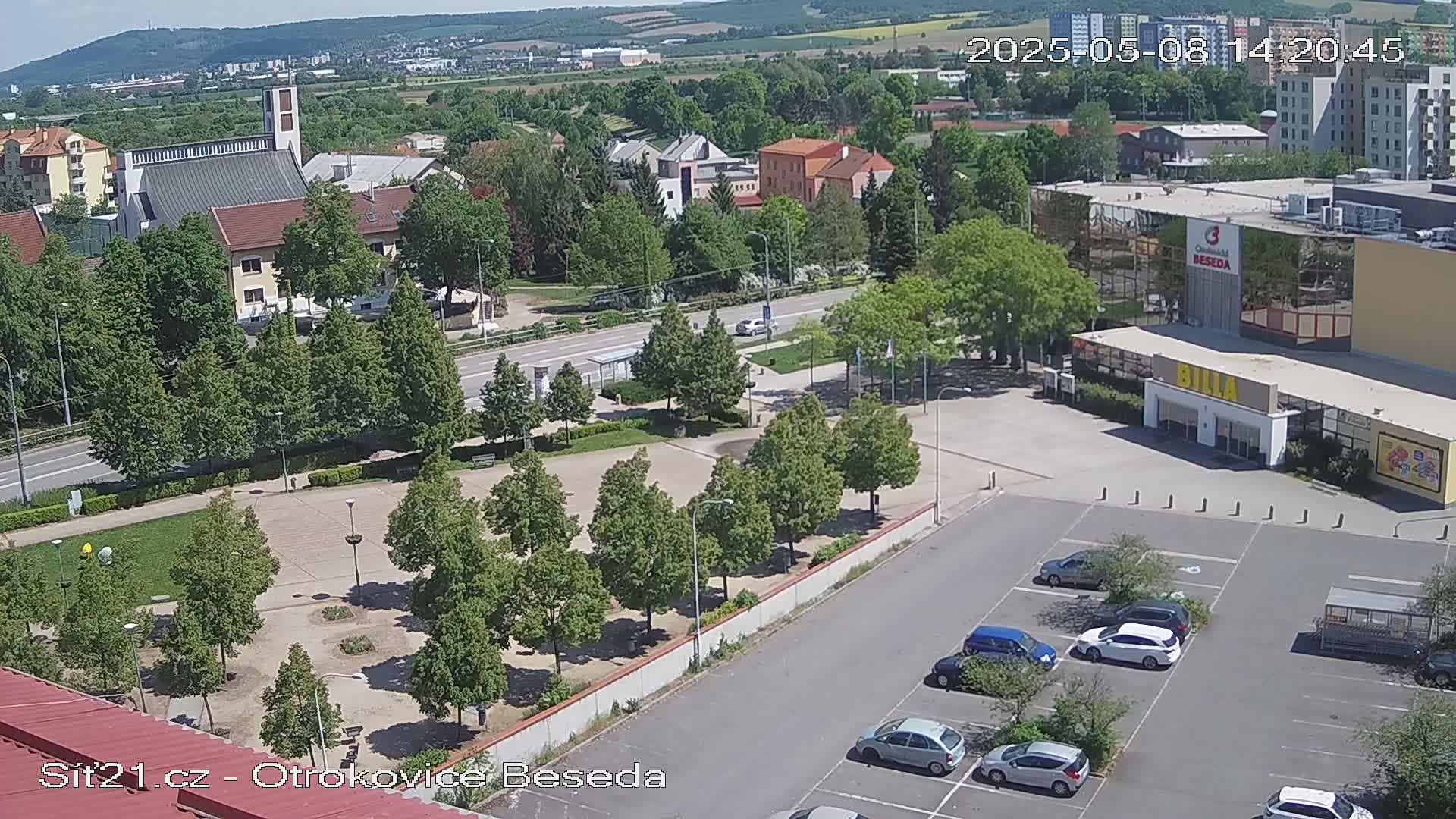 An aerial view of a town square with a church and a large parking lot on a sunny day.