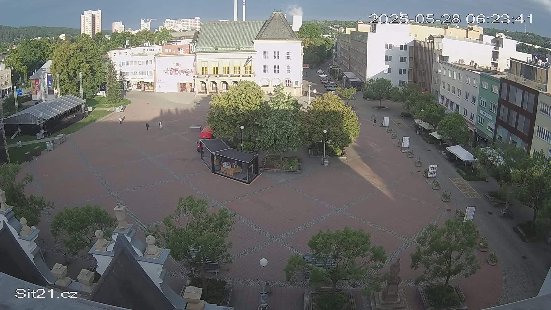 A mostly empty town square with buildings surrounding it, under sunny skies.