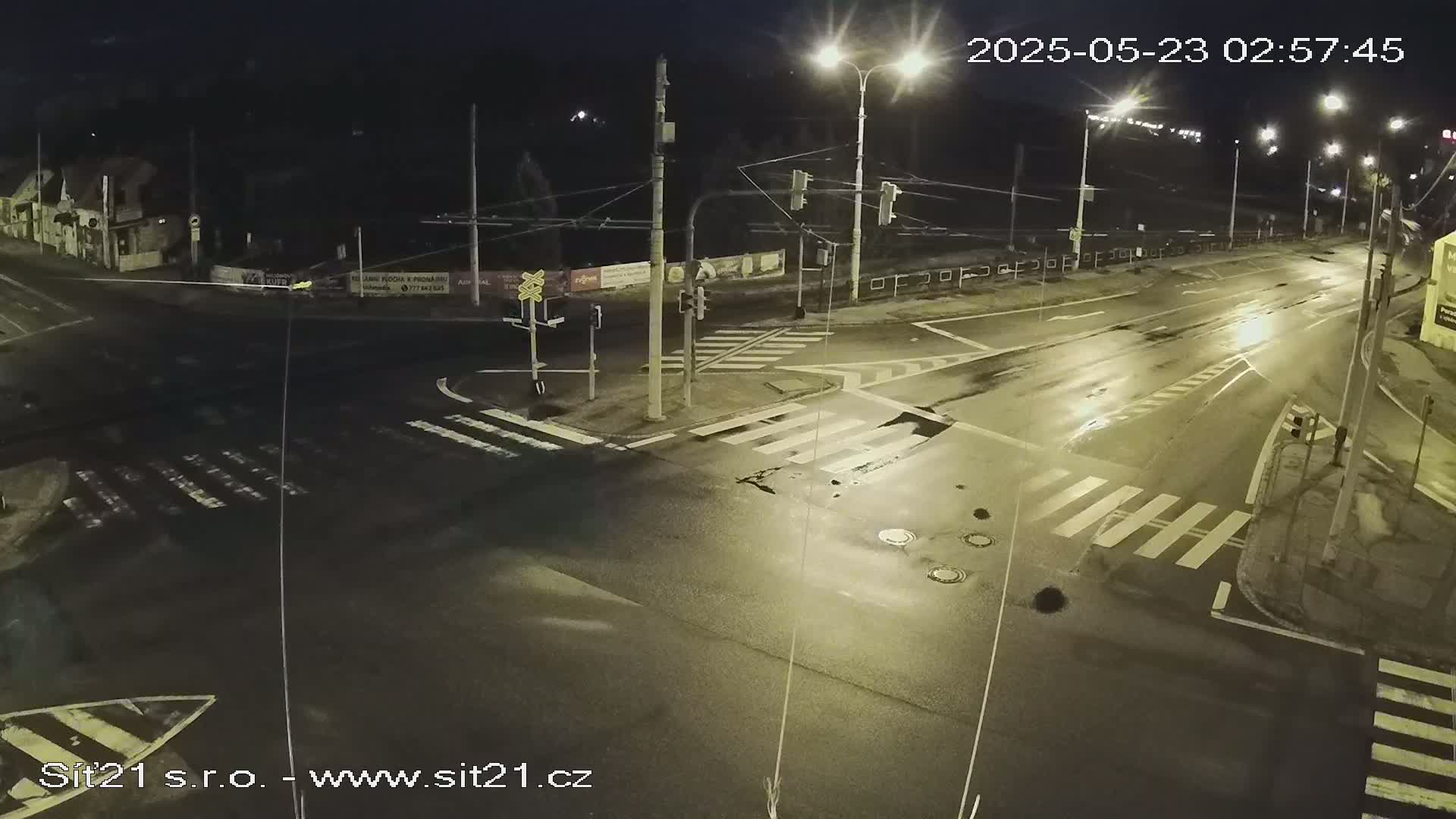 A wet, empty intersection at night, illuminated by streetlights.