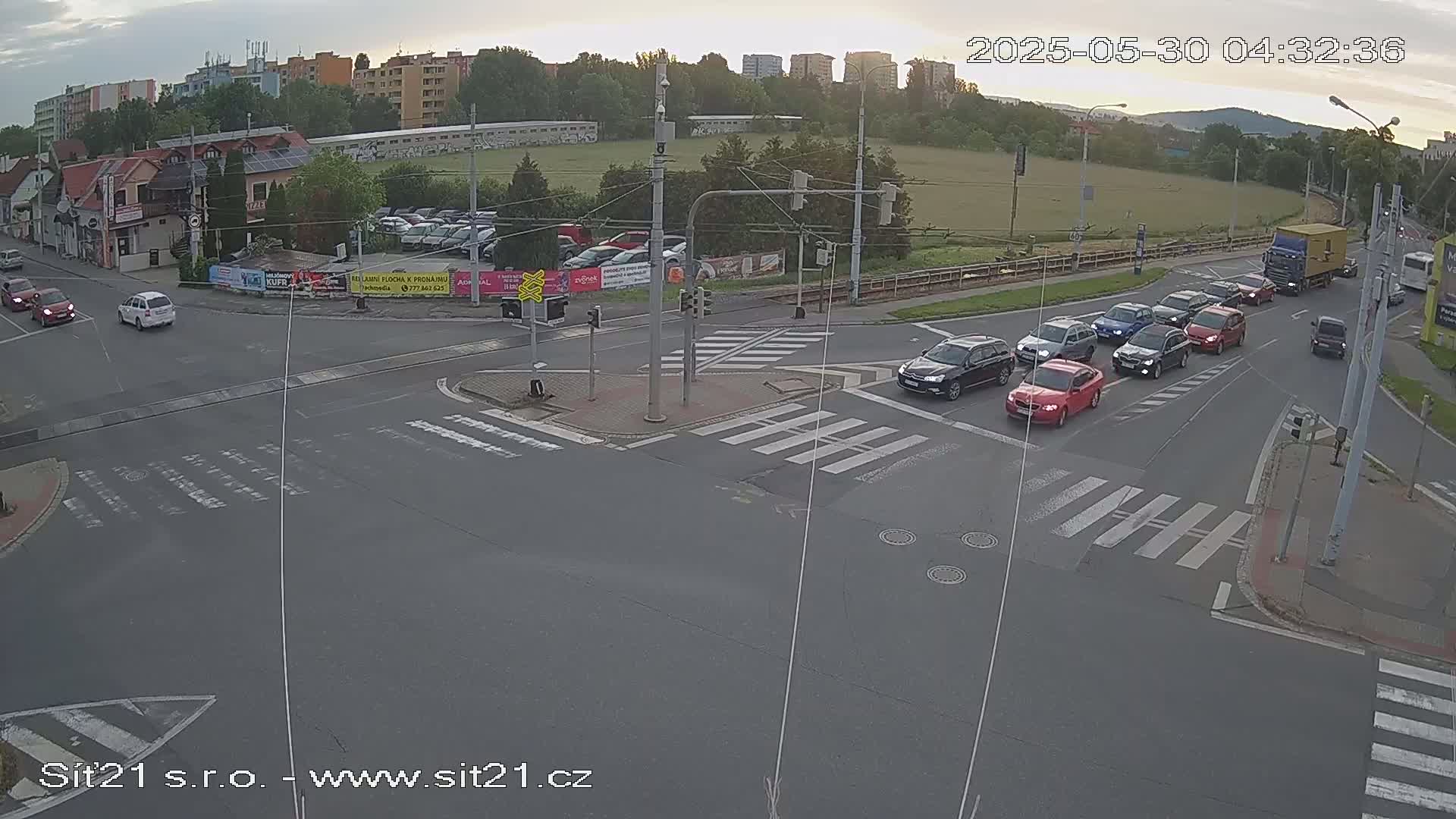 Several cars are stopped at a crosswalked intersection on a mostly overcast day.