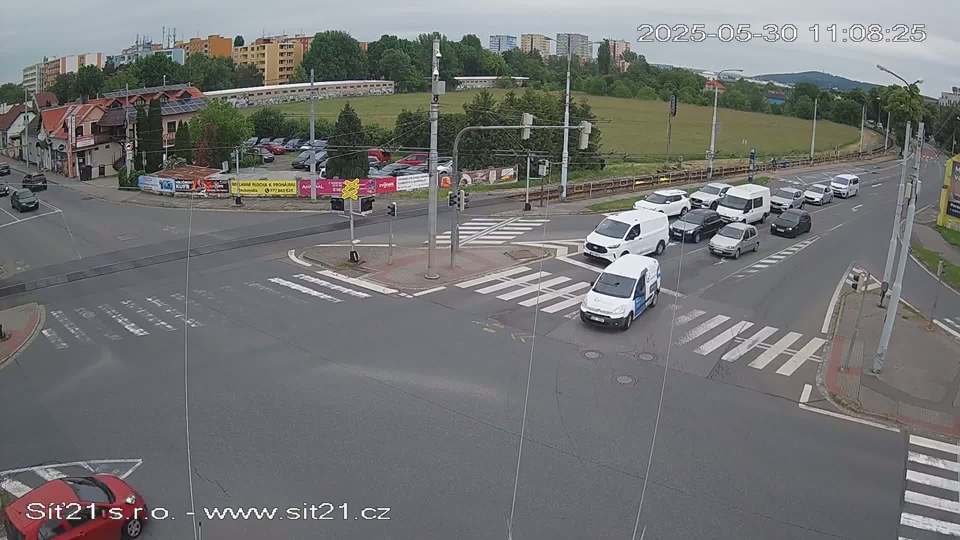 A street intersection with several cars stopped at a traffic light on an overcast day.