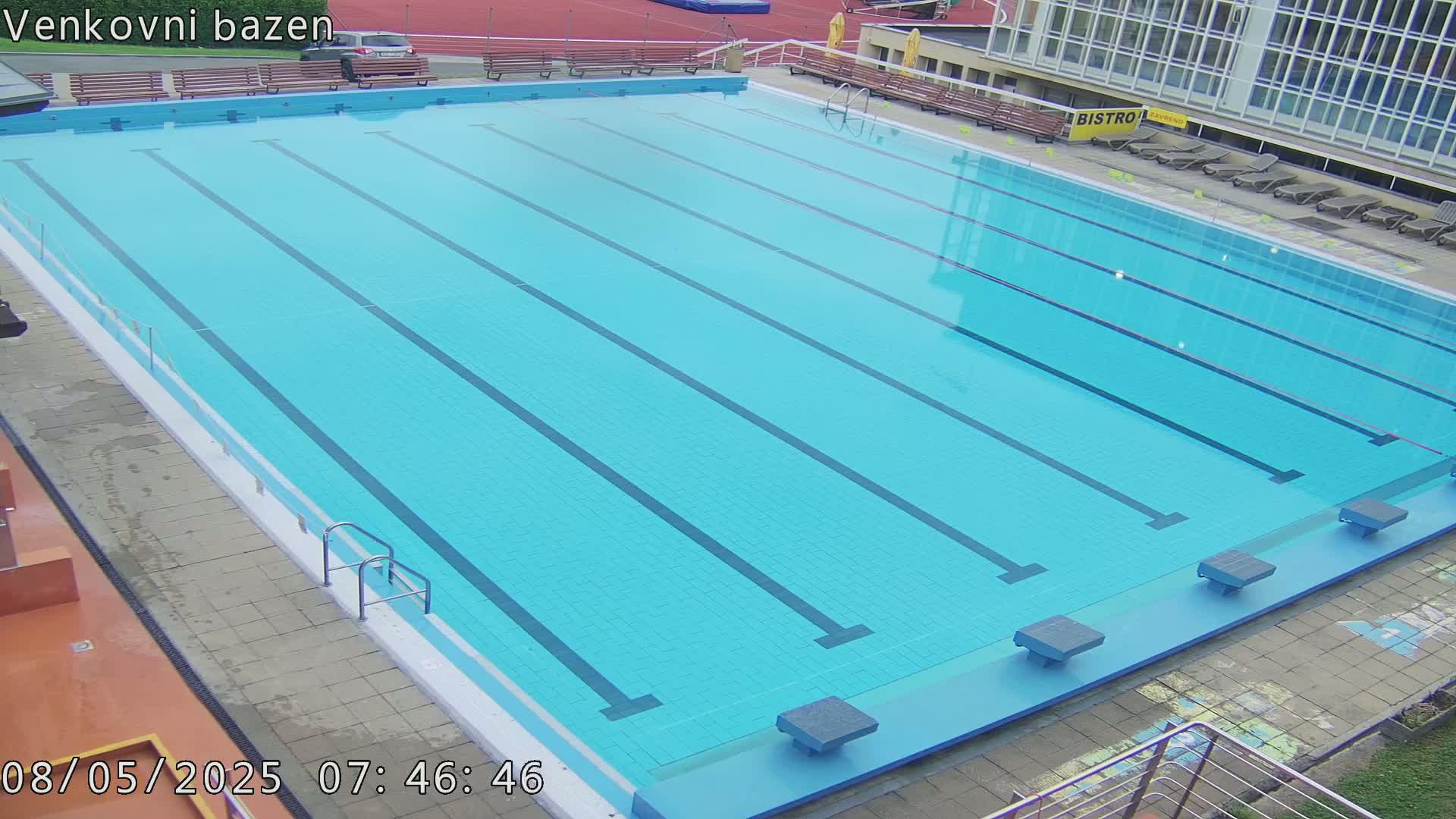 An outdoor swimming pool with multiple lanes is empty on a clear day.
