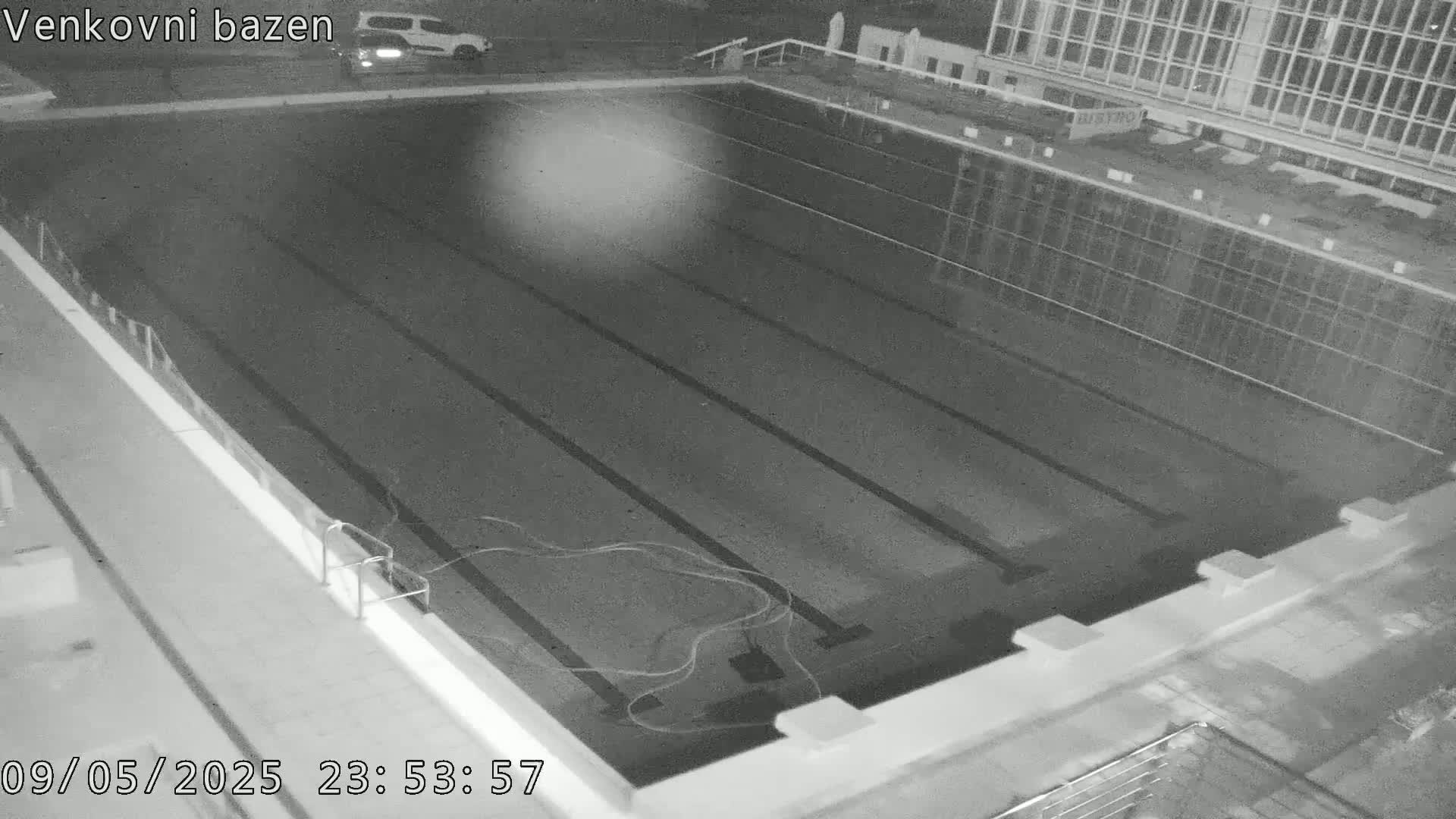 An empty outdoor swimming pool is visible at night.