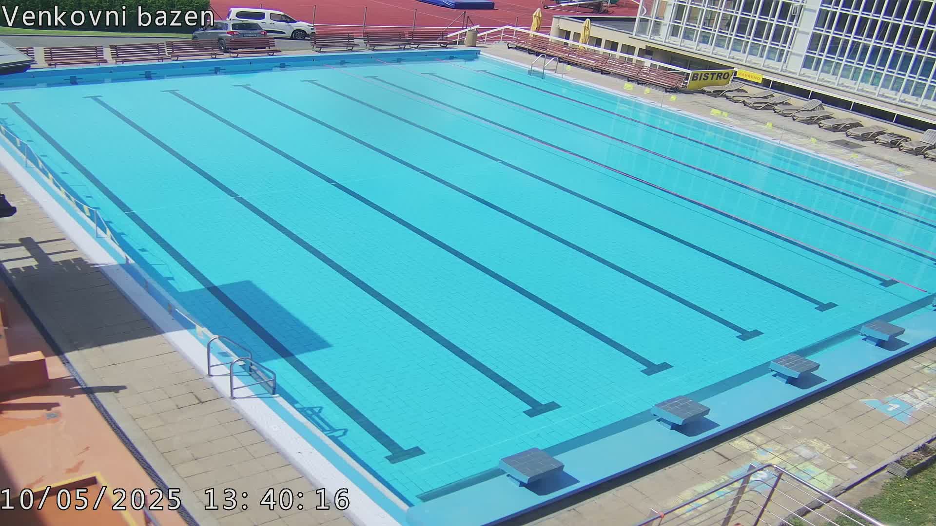 An outdoor swimming pool with multiple lanes is shown on a sunny day.