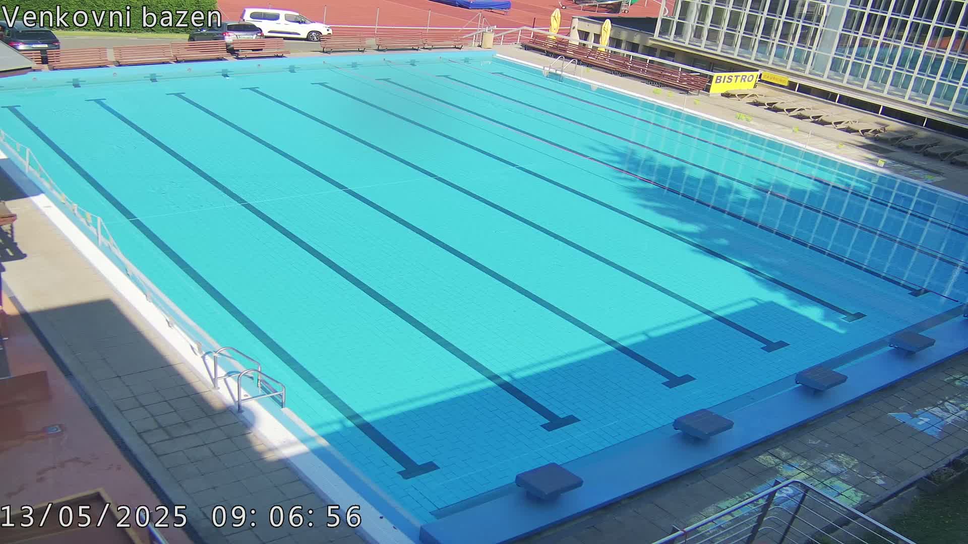 An outdoor, sunny view of a large, empty swimming pool with multiple lanes.