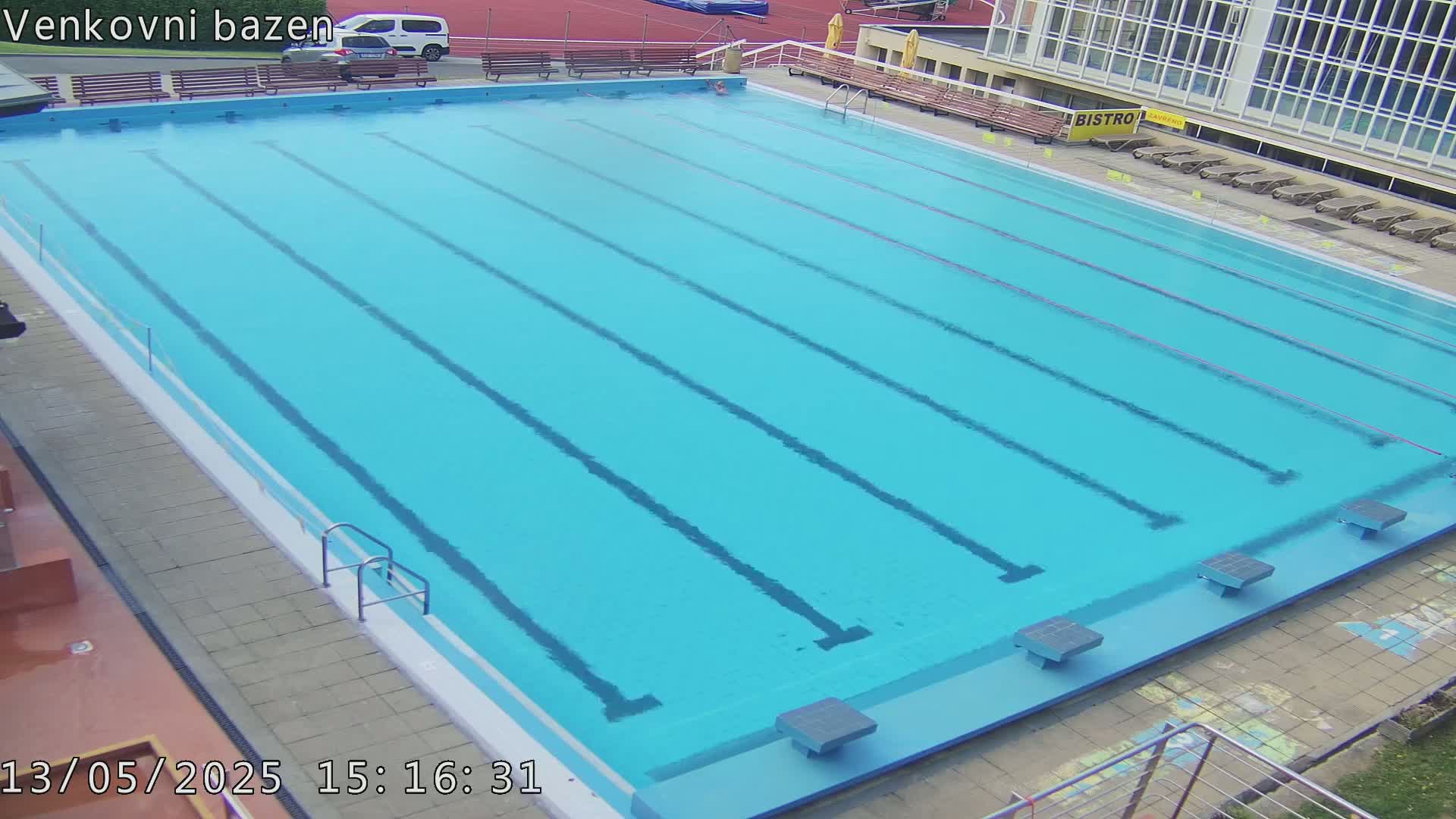 An outdoor swimming pool with multiple lanes is shown, under what appears to be sunny conditions.