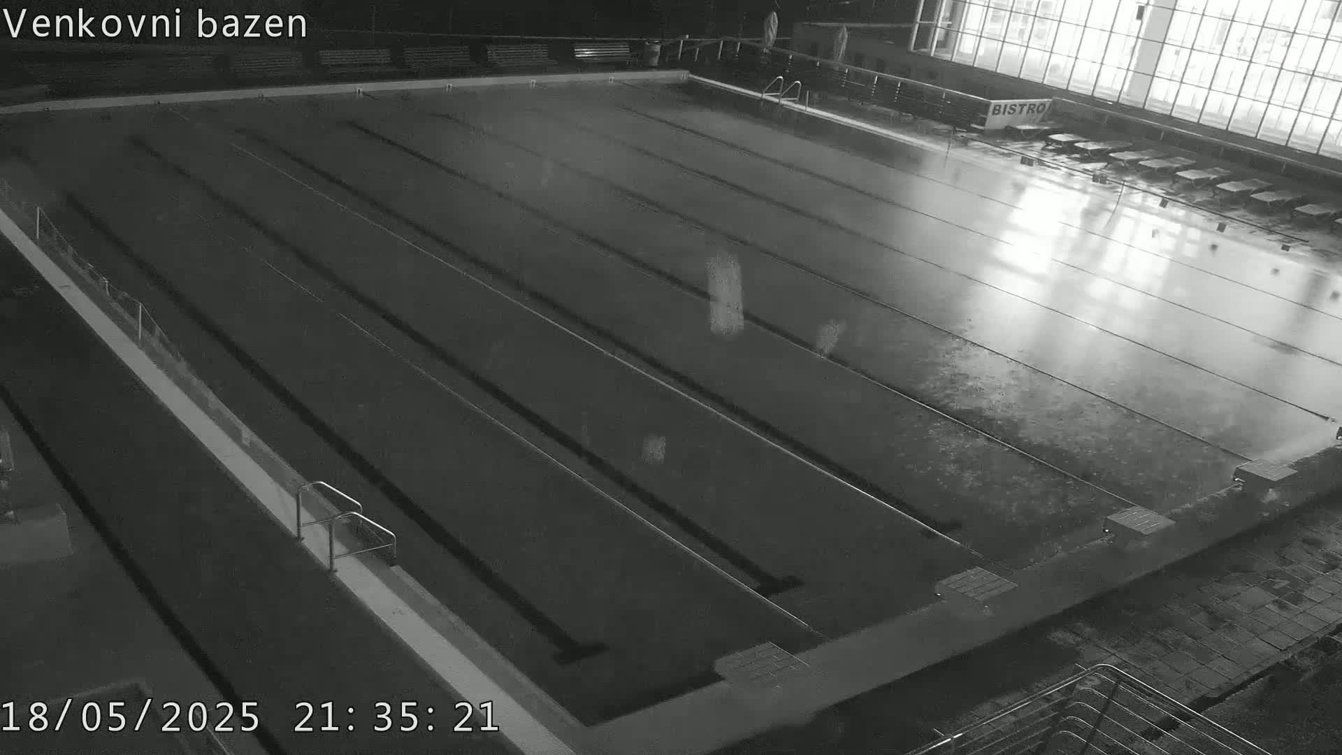 An empty, dark swimming pool is viewed from above at night.