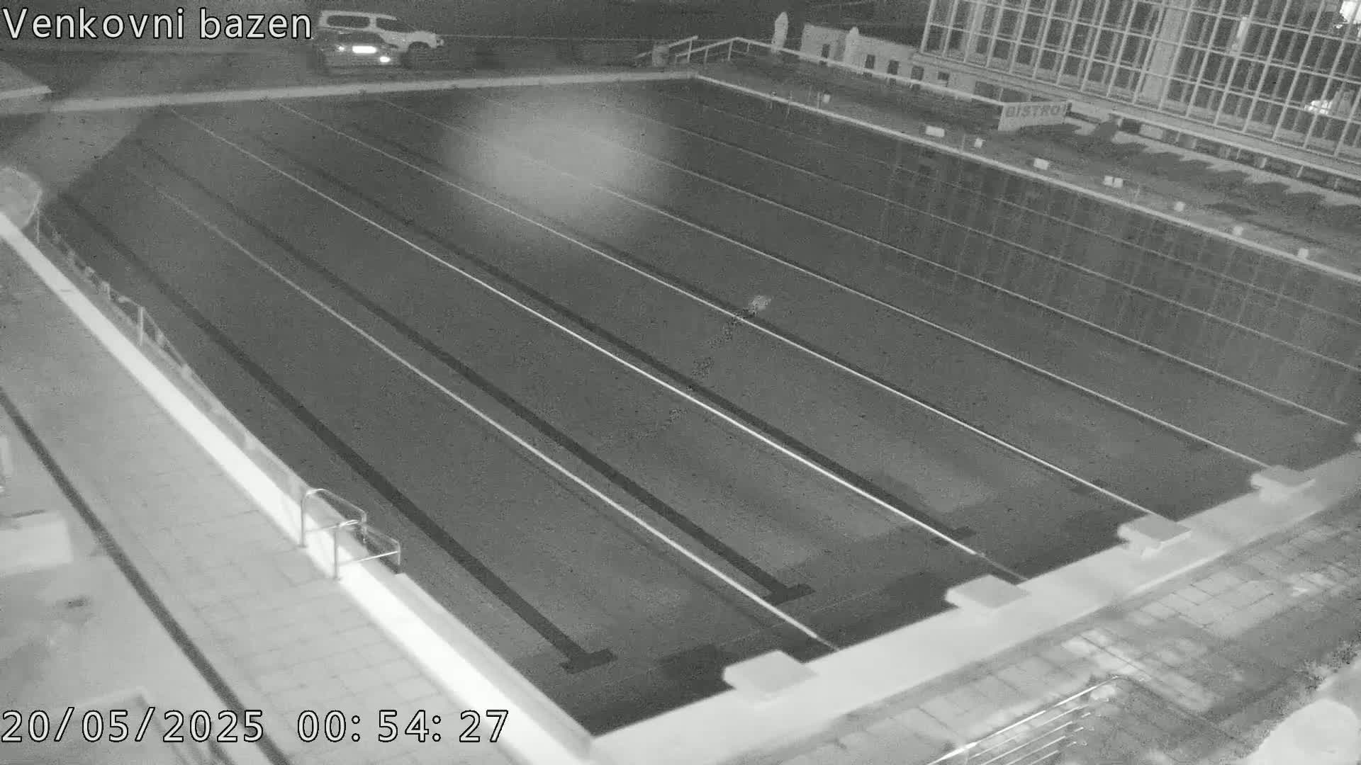 An empty outdoor swimming pool is shown at night.