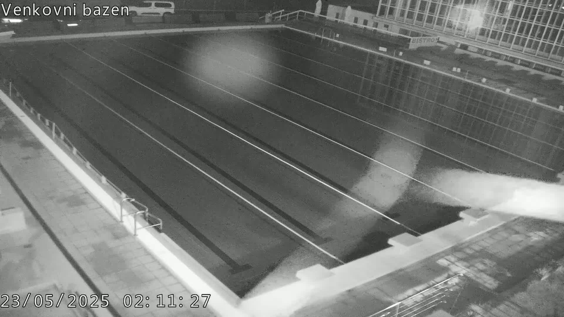 An empty outdoor swimming pool is shown at night.
