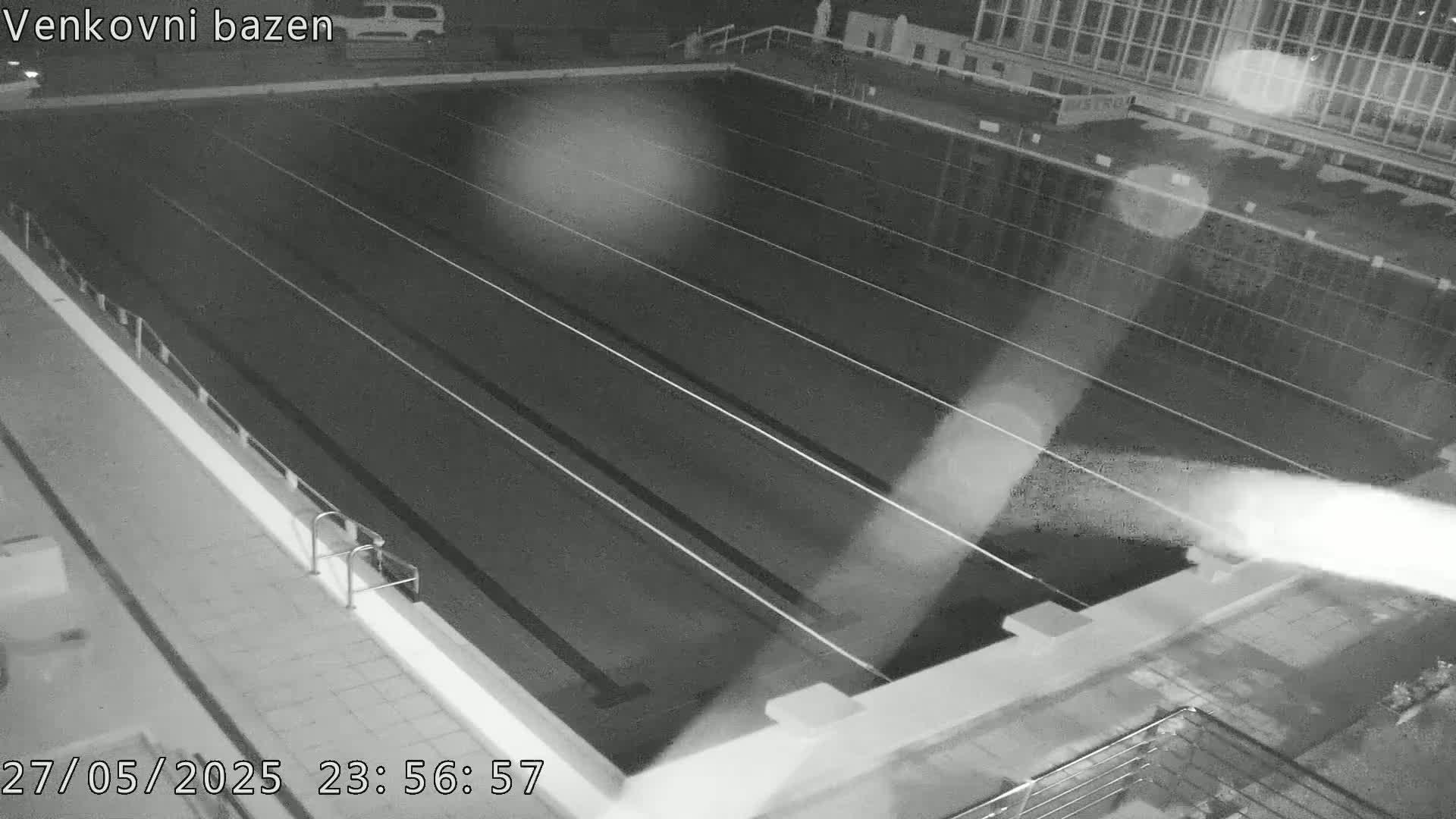 A nighttime, high-angle view of an empty outdoor swimming pool with lane dividers.