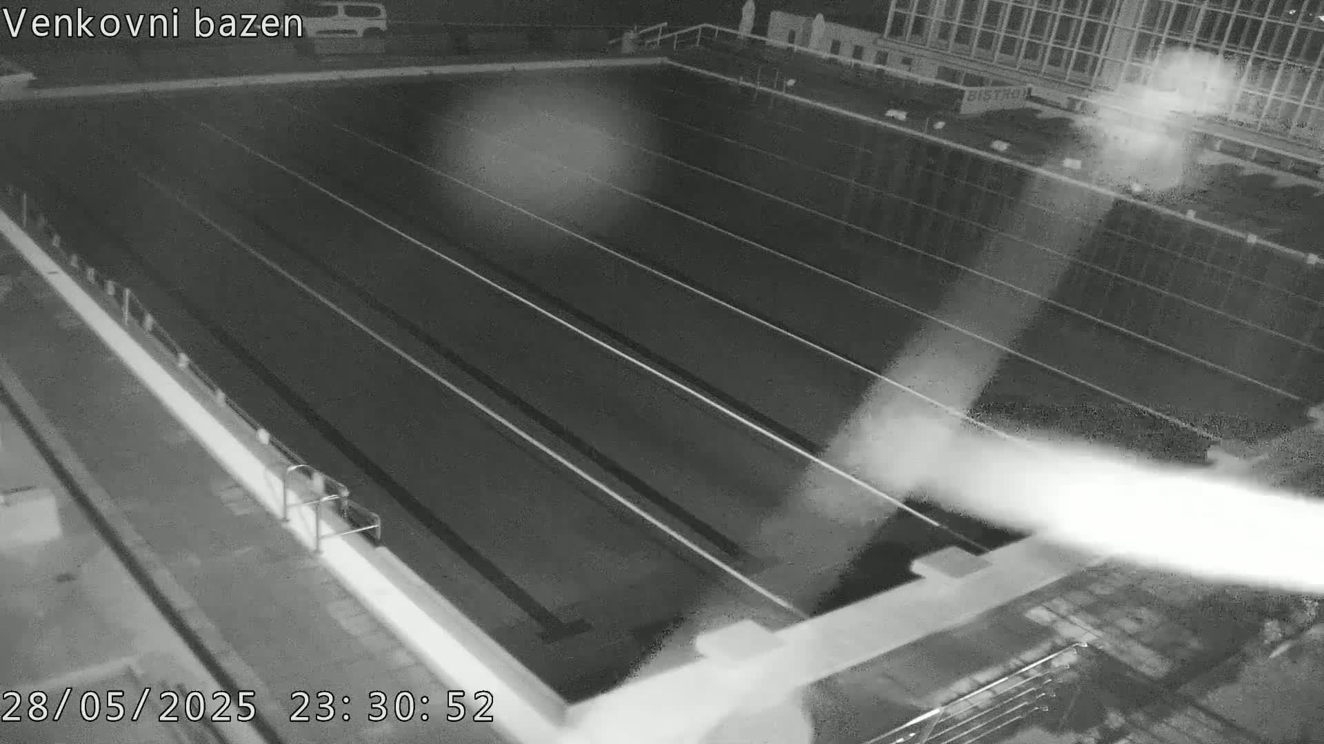 An empty, dark swimming pool at night is seen from above.