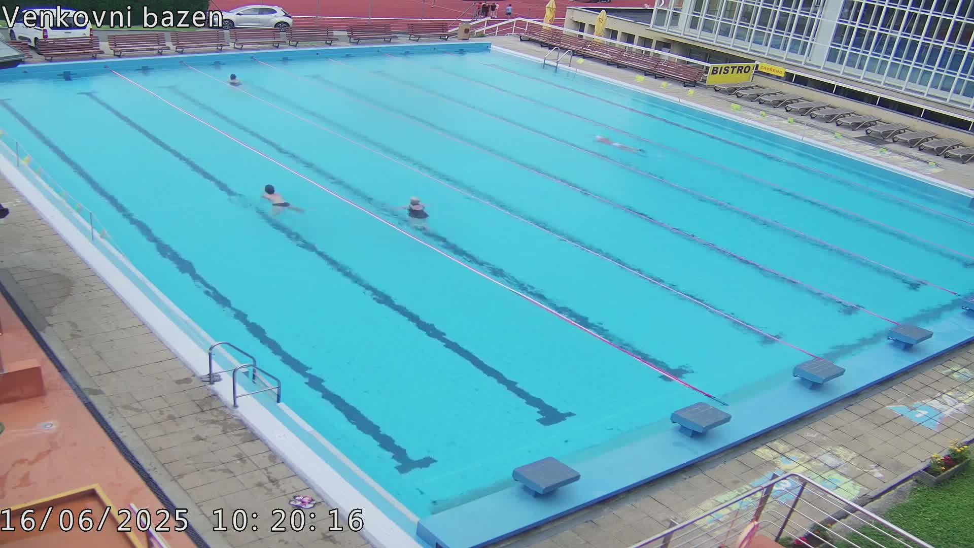 A large outdoor swimming pool with several people swimming in it.