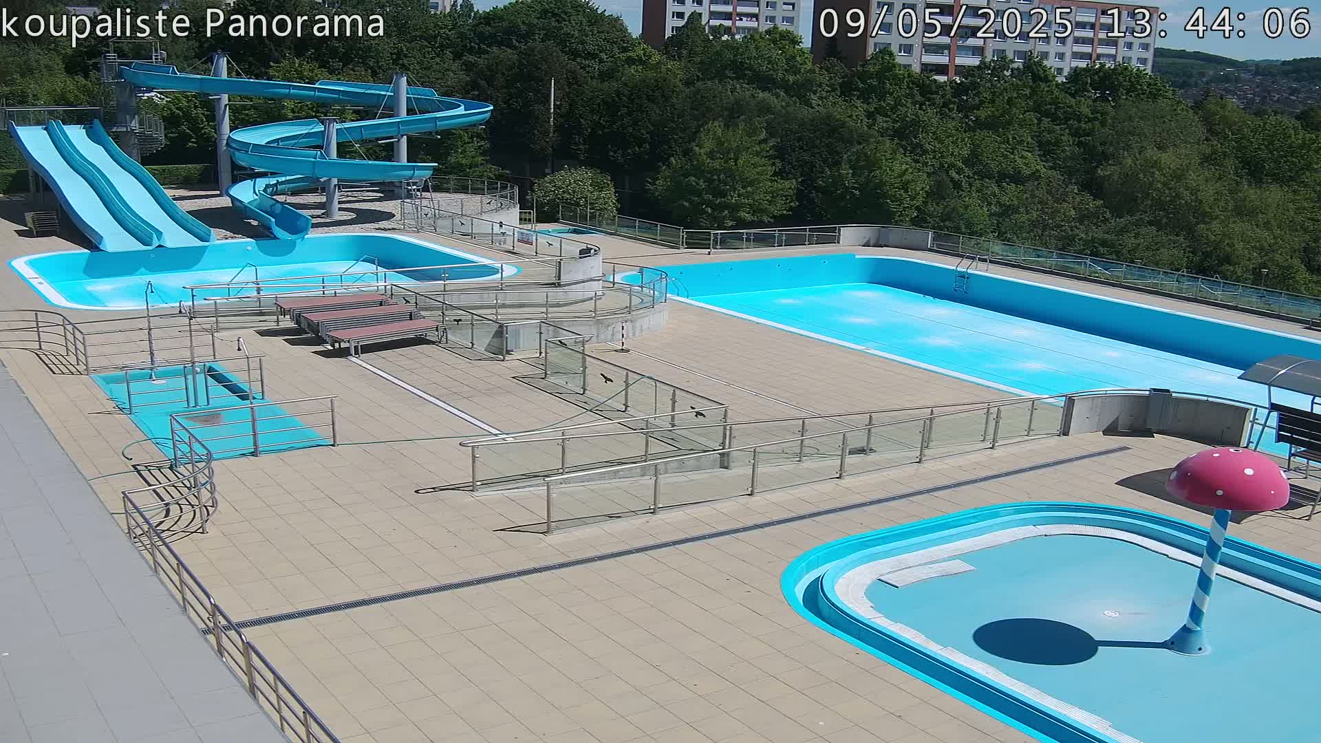 An outdoor pool complex with multiple pools, slides, and ramps on a sunny day.