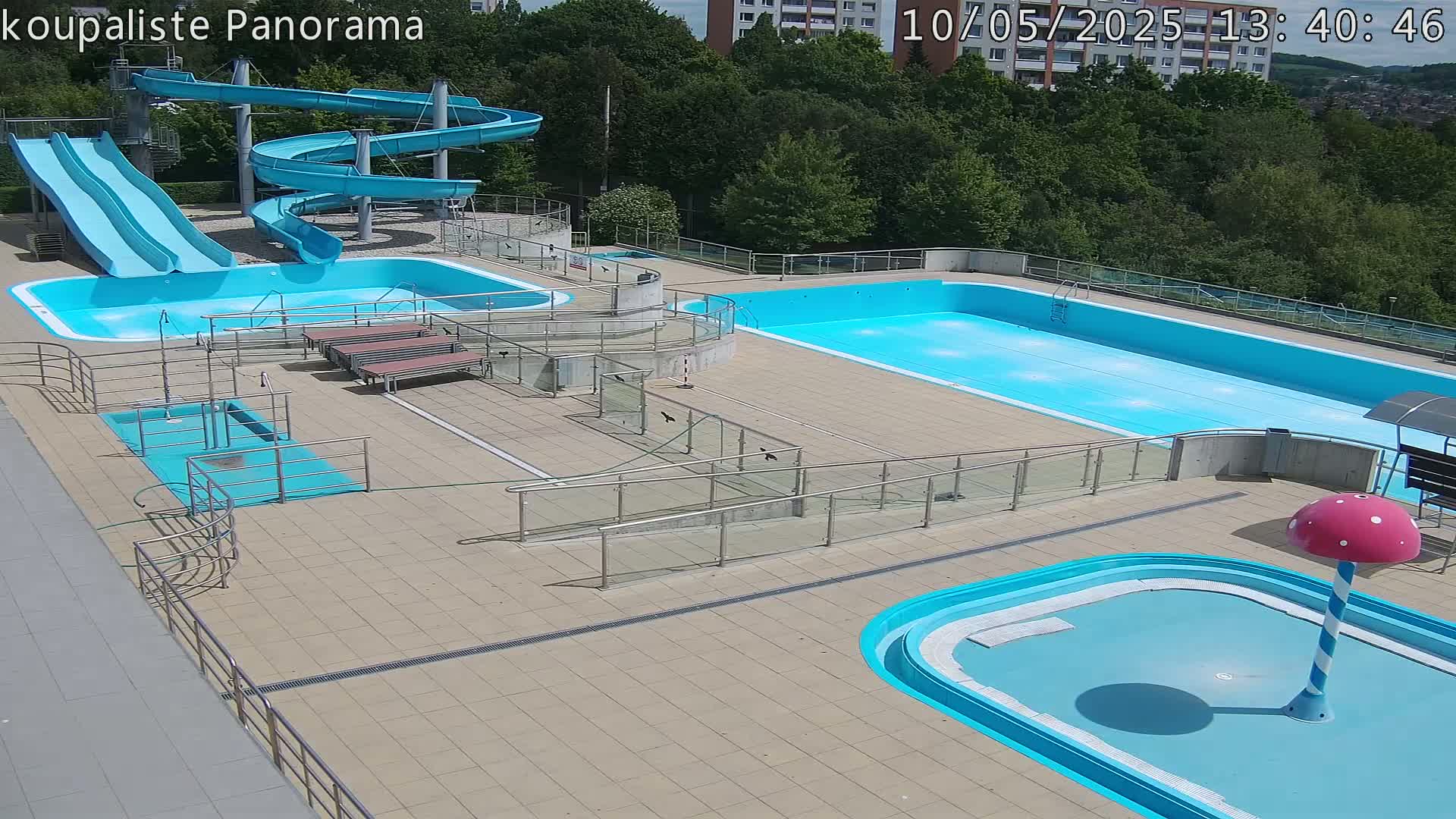 An outdoor swimming complex with multiple pools, water slides, and ramps under sunny conditions.