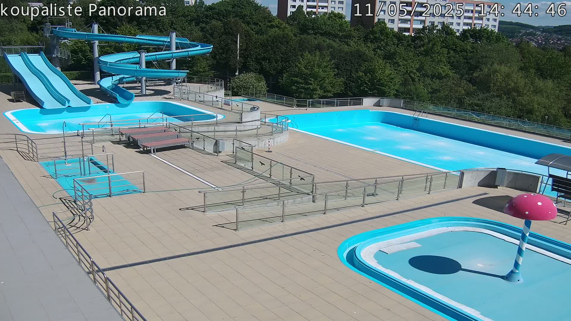 An outdoor pool complex with several pools, water slides, and ramps, all under sunny skies.