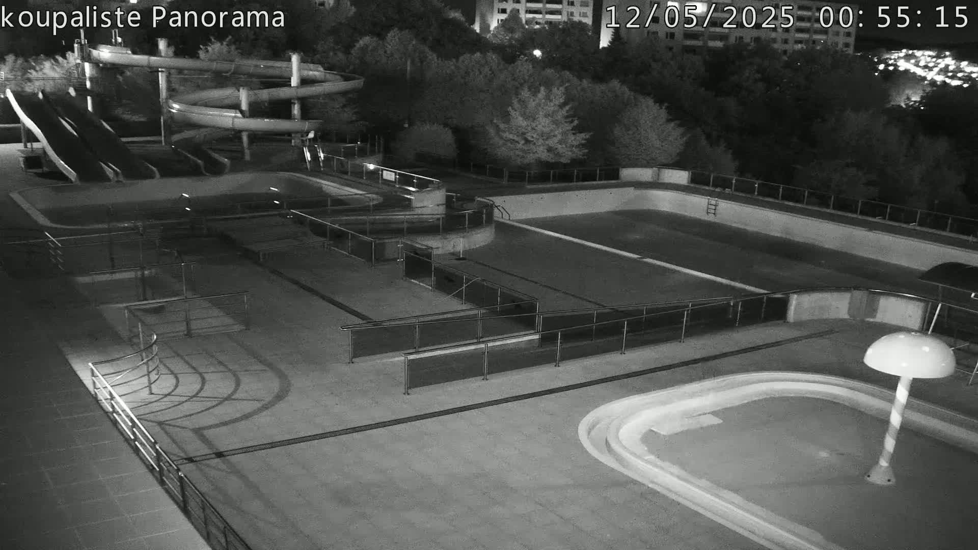 An empty outdoor pool area with water slides is seen at night.