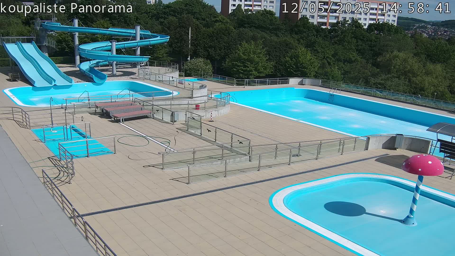 An outdoor pool complex with several pools, slides, and ramps, on a sunny day.