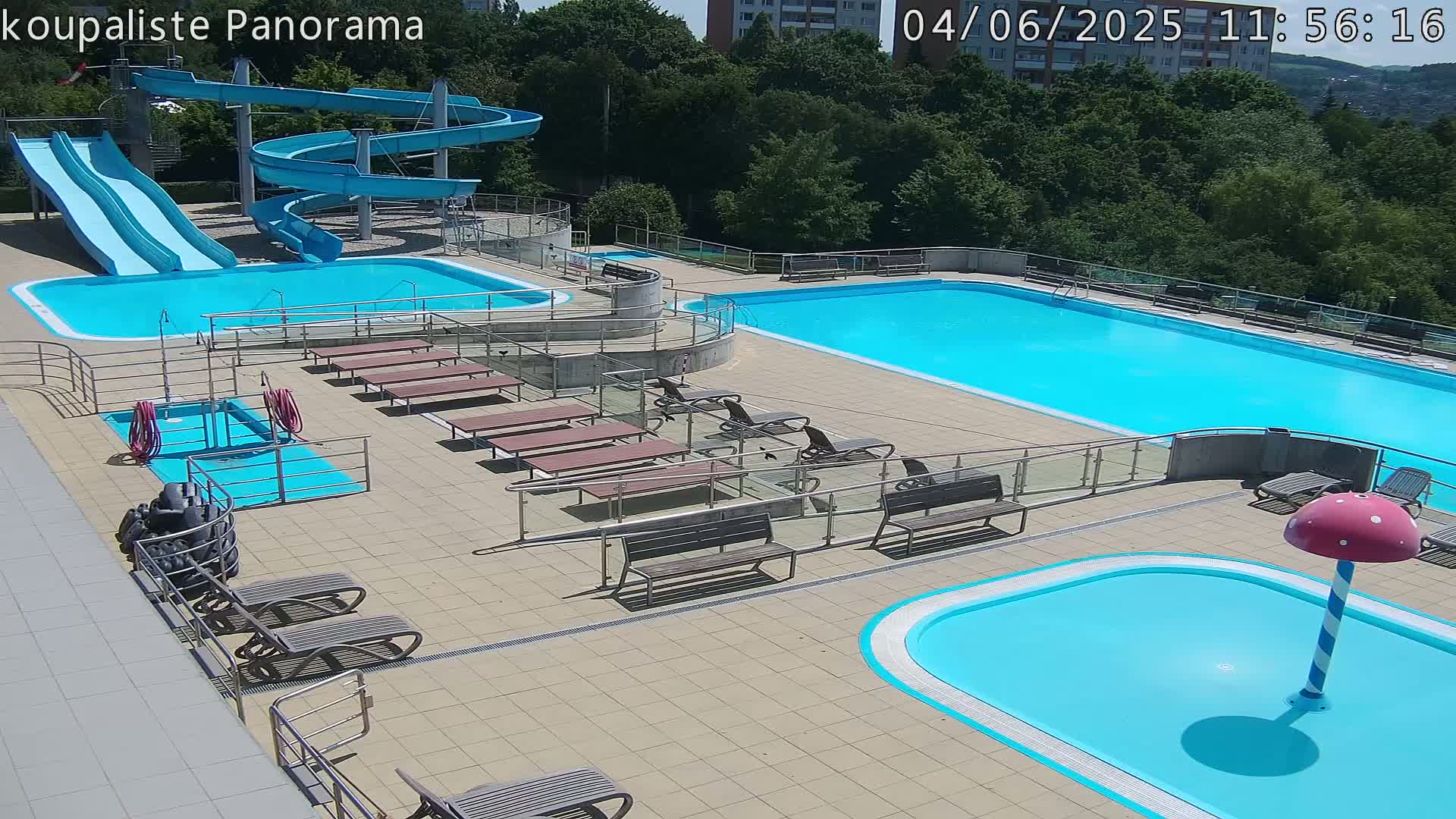 An outdoor pool complex with multiple pools, water slides, and lounge chairs on a sunny day.