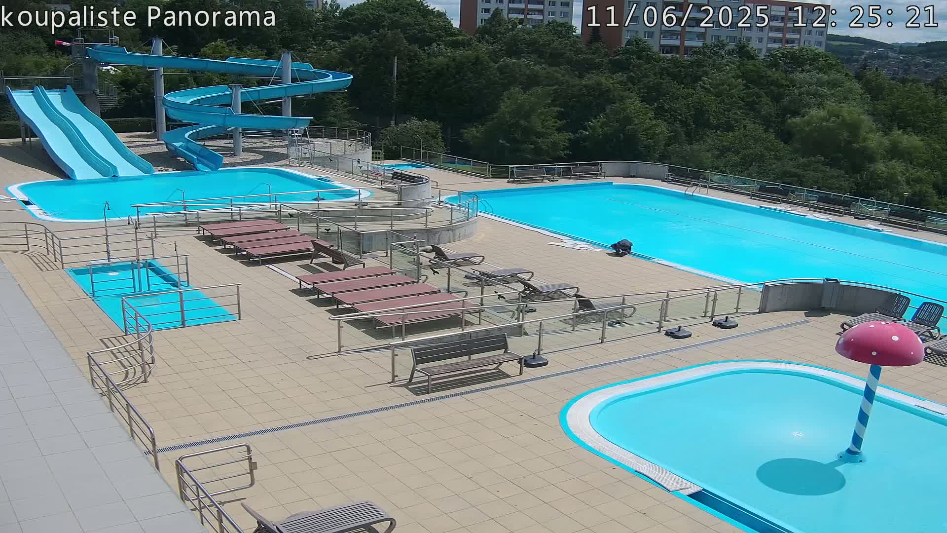An outdoor pool complex with multiple pools, water slides, and lounge chairs on a sunny day.