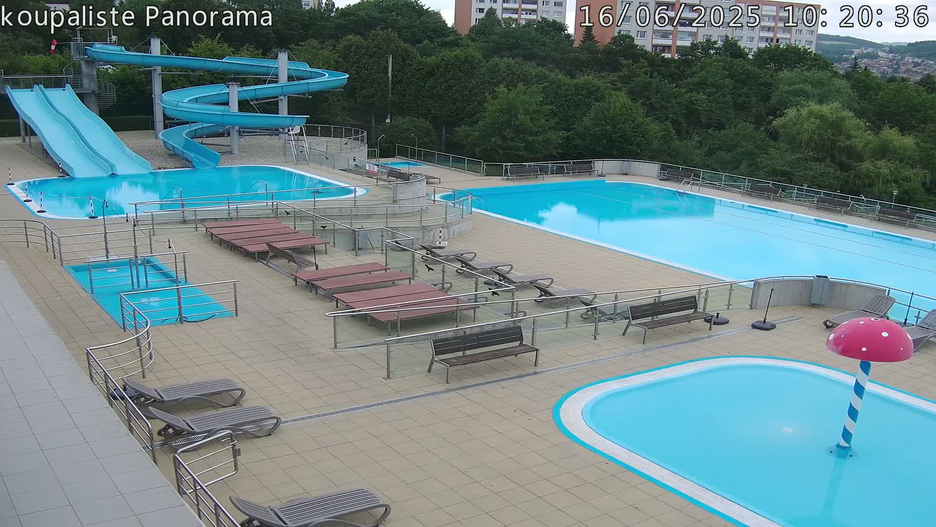 An outdoor pool complex with multiple pools, water slides, lounge chairs, and a mushroom-shaped water feature.