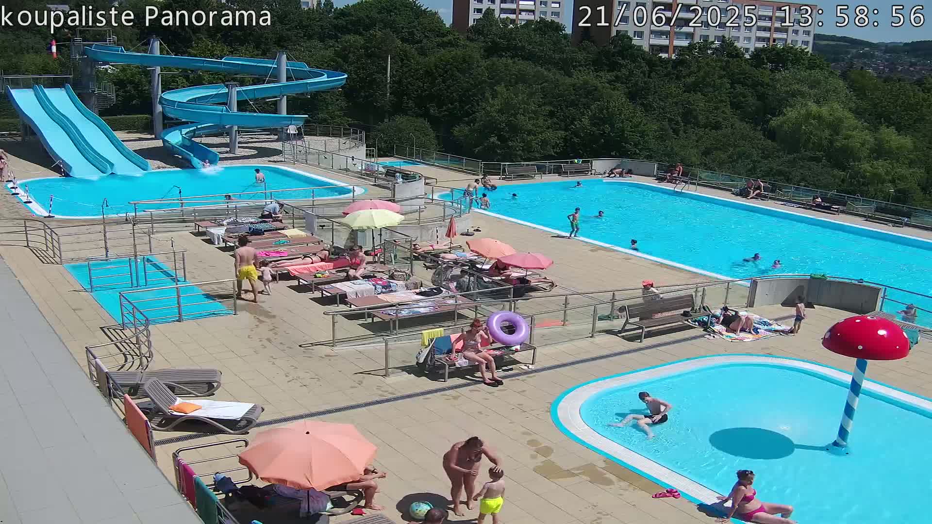 An outdoor swimming pool complex with multiple pools, water slides, and sunbathers on a sunny day.