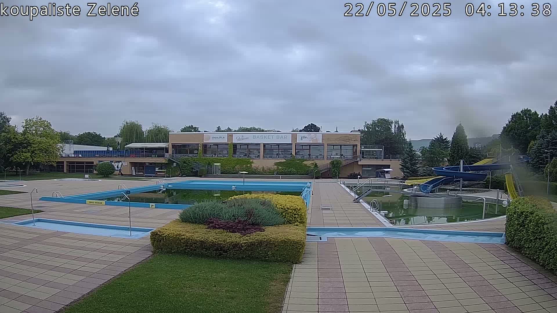 An outdoor pool complex with a building and water slides under an overcast sky.