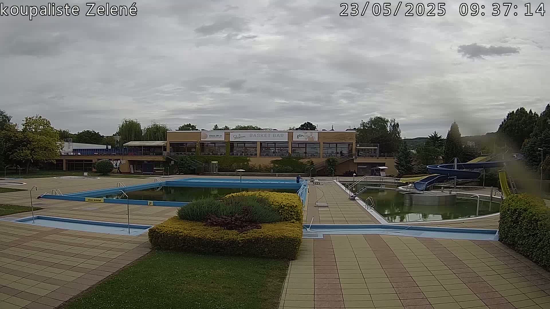 An outdoor pool complex with water slides sits under an overcast sky.