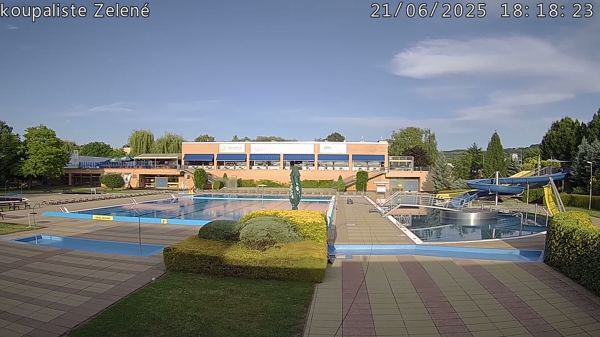 A large outdoor swimming pool complex with water slides is visible under a mostly sunny sky.