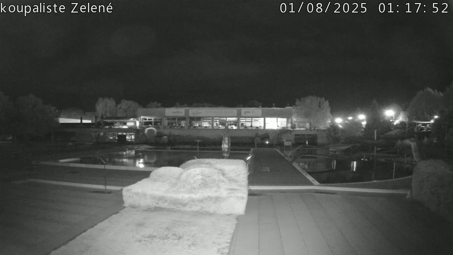 A nighttime, low-light view of a swimming pool and building complex.