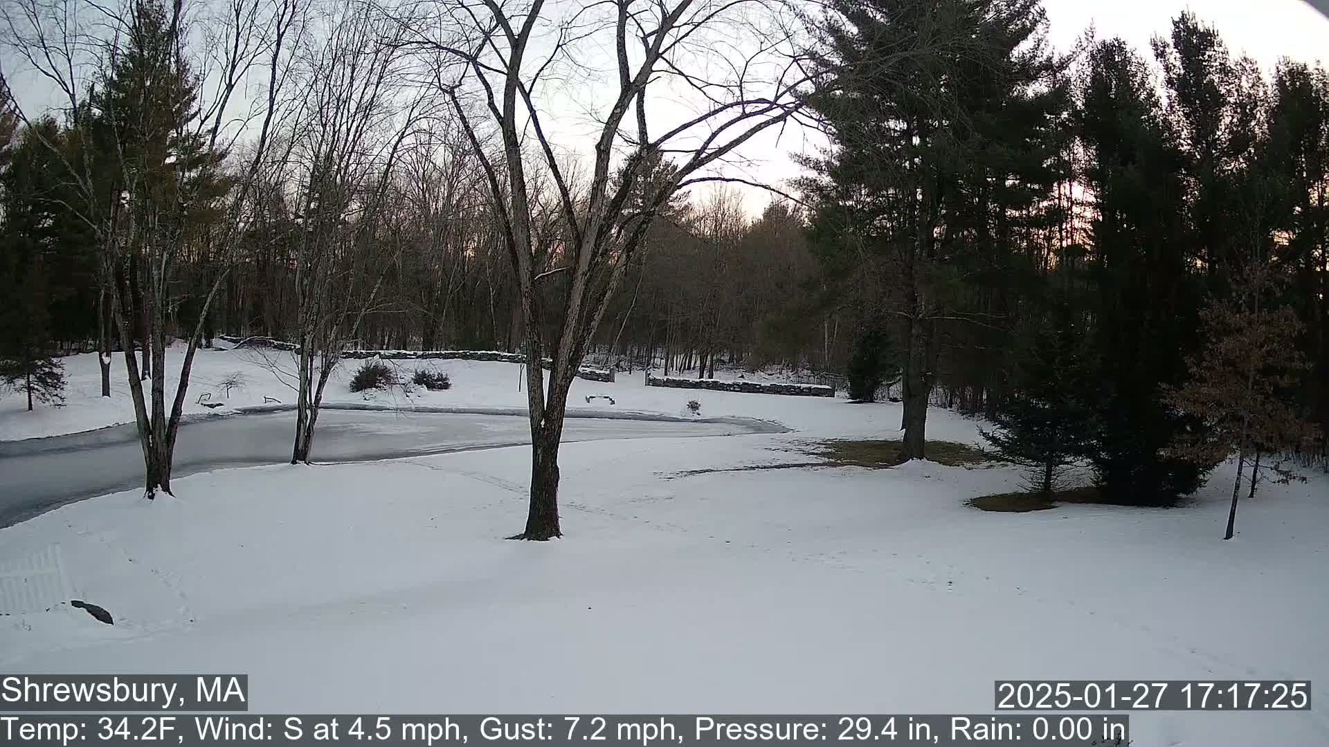 A snow-covered yard with bare trees and a partially frozen body of water is visible in the twilight.