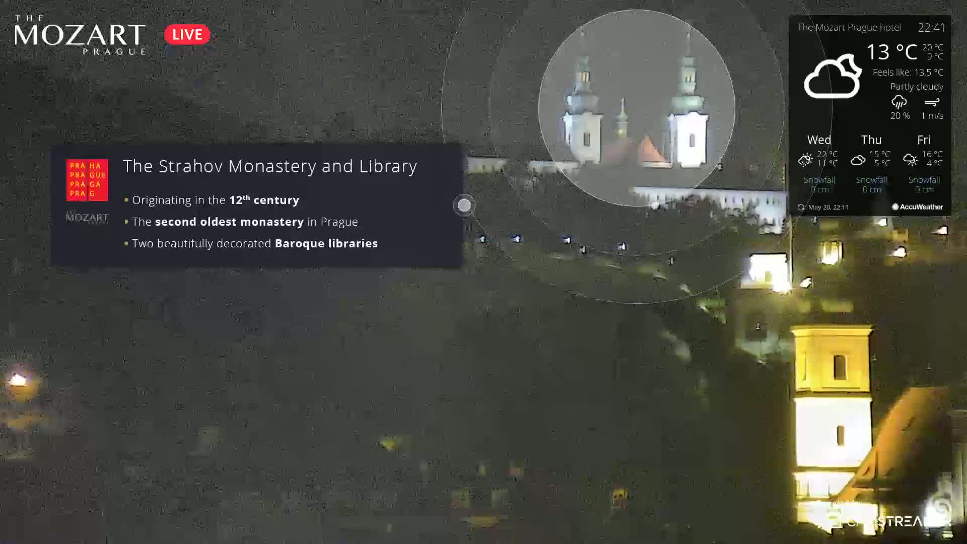 A nighttime, partly cloudy view of Strahov Monastery and Library in Prague, with some lights visible on the buildings and in the surrounding area.