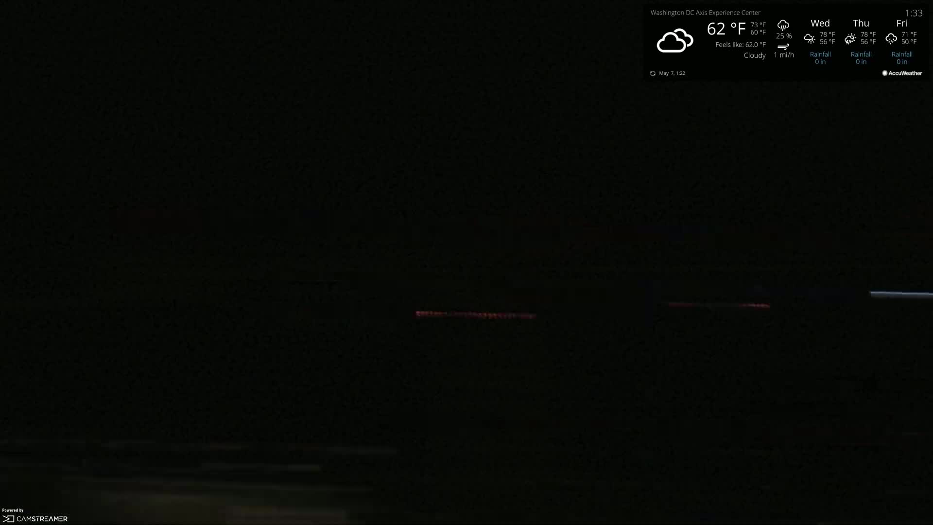 A nighttime, cloudy scene shows a dimly lit roadway with a faint reddish glow in the distance.