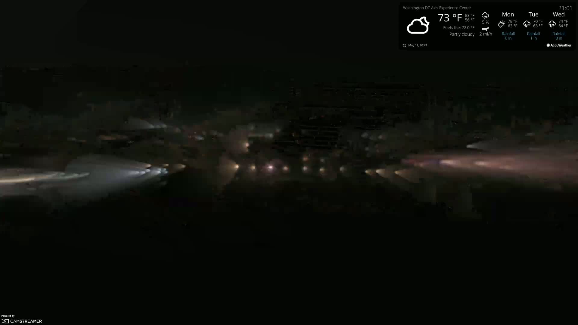 Headlights from numerous vehicles create streaks of light on a dark, partly cloudy night.
