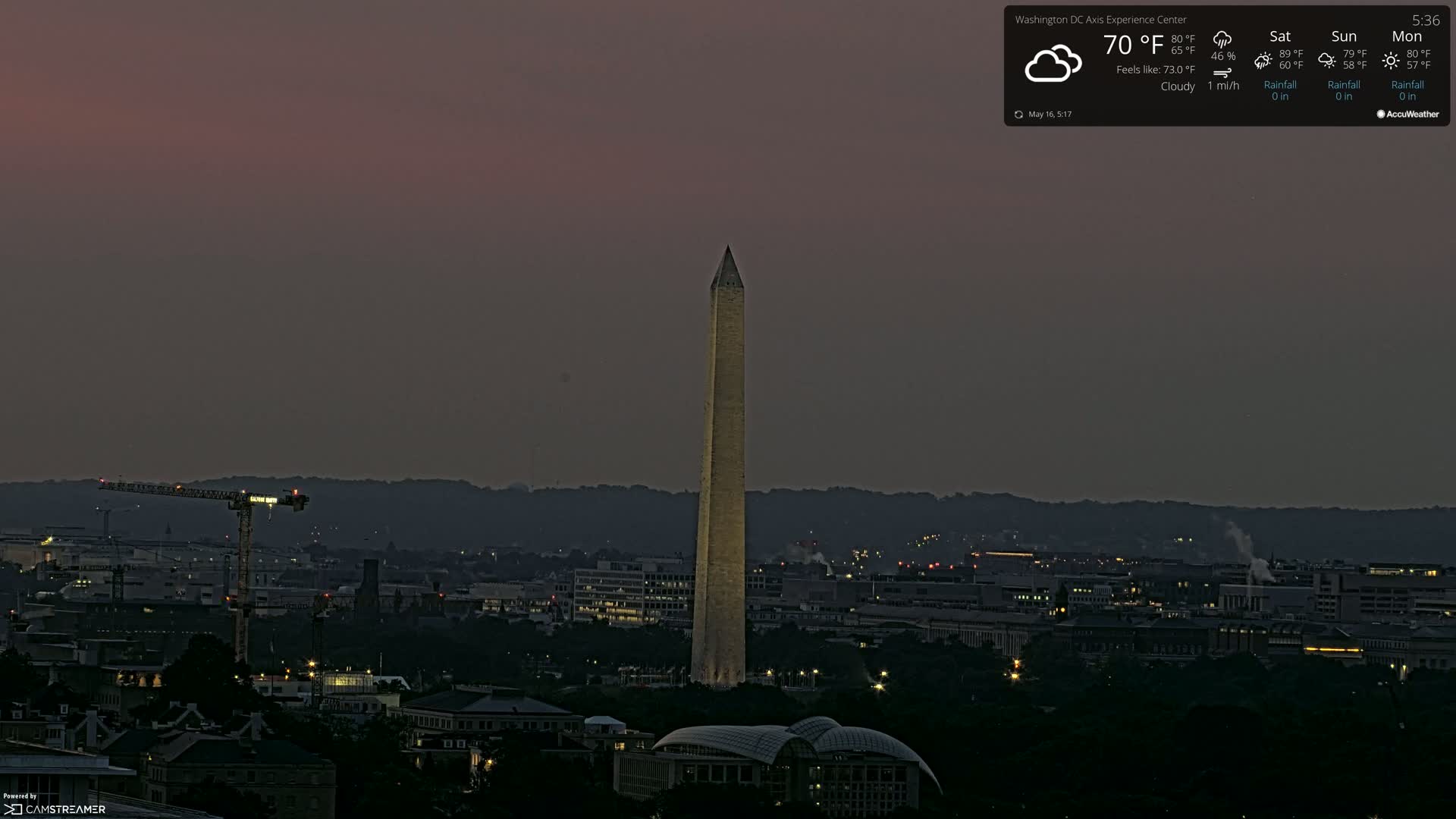 Under a cloudy, dusky sky, the Washington Monument stands tall over a cityscape at night.