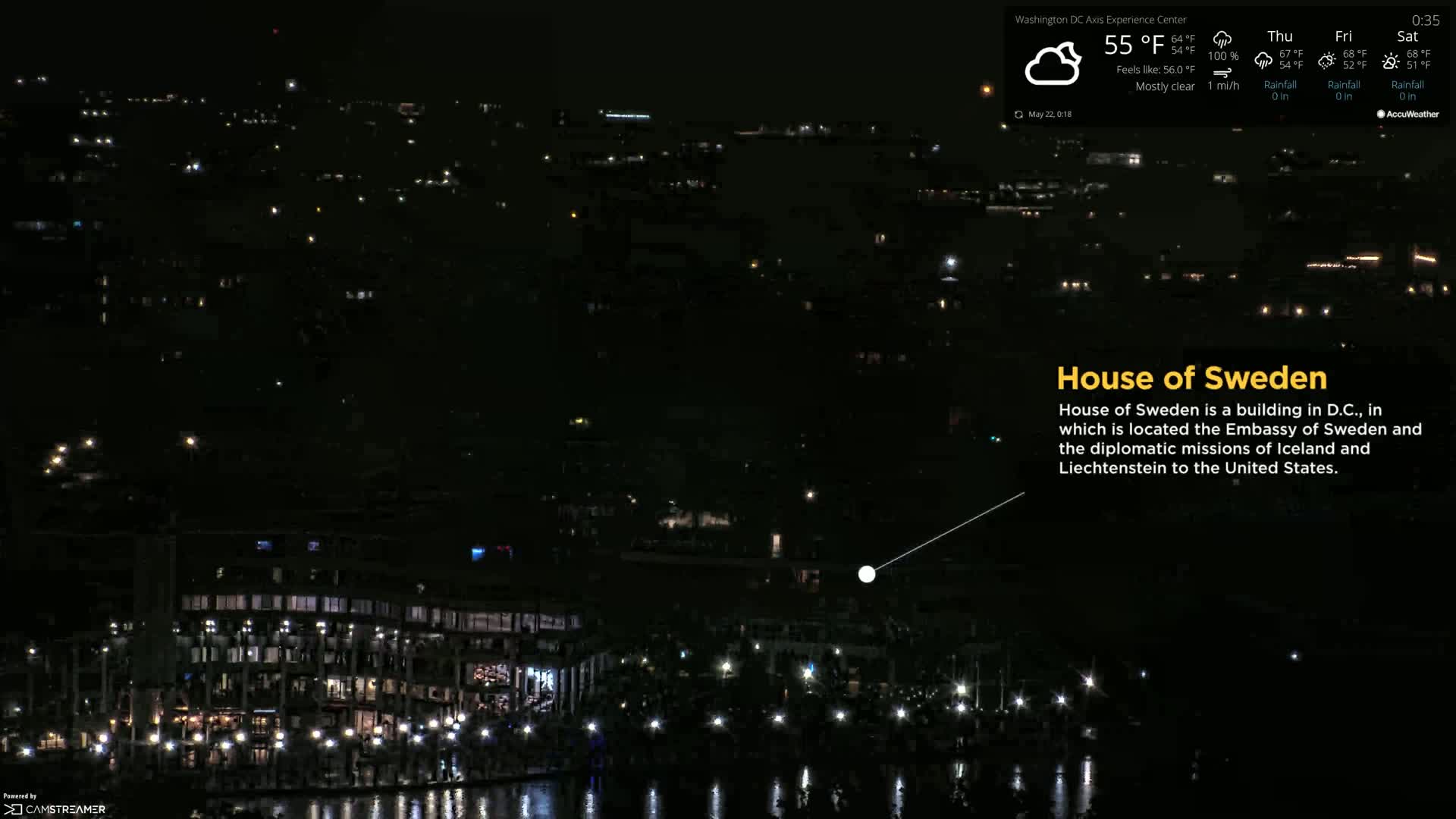 A nighttime aerial view of a city waterfront, mostly dark with scattered lights, under mostly clear skies and a temperature of 55°F.