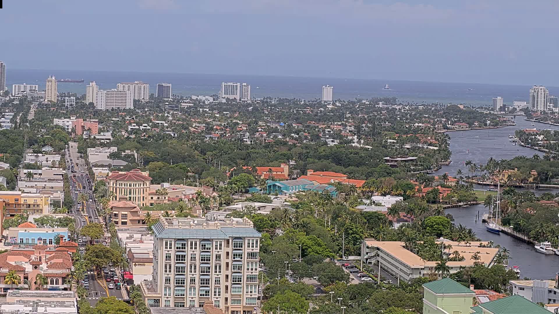 A coastal city with a waterway winds through a residential area, under a hazy, sunny sky.