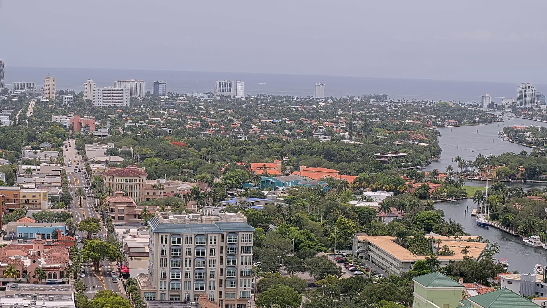 A coastal city with a network of waterways, surrounded by lush green vegetation under an overcast sky.