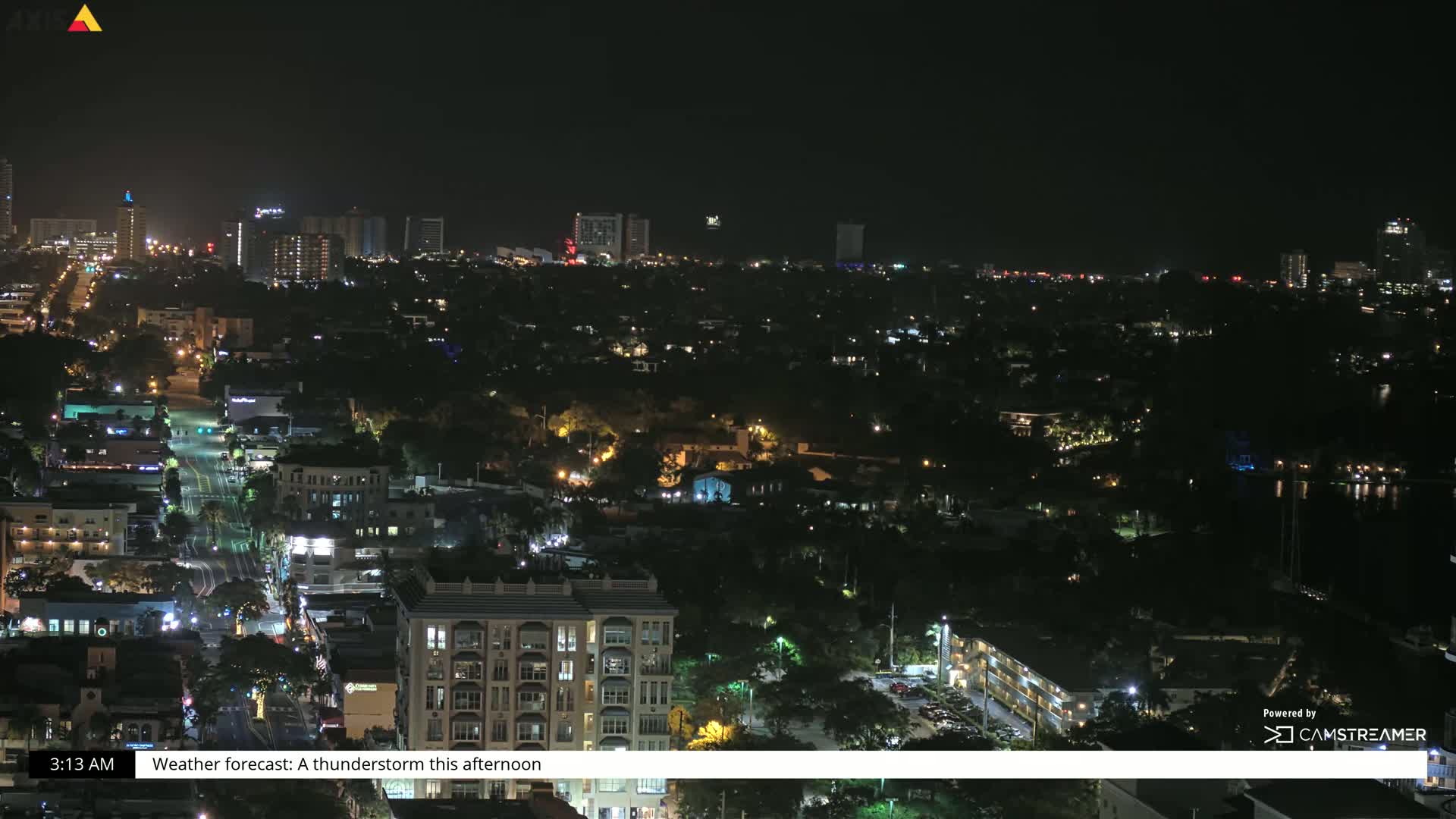 A nighttime aerial view of a city with scattered lights, showing a mix of residential and commercial buildings under a clear, dark sky.