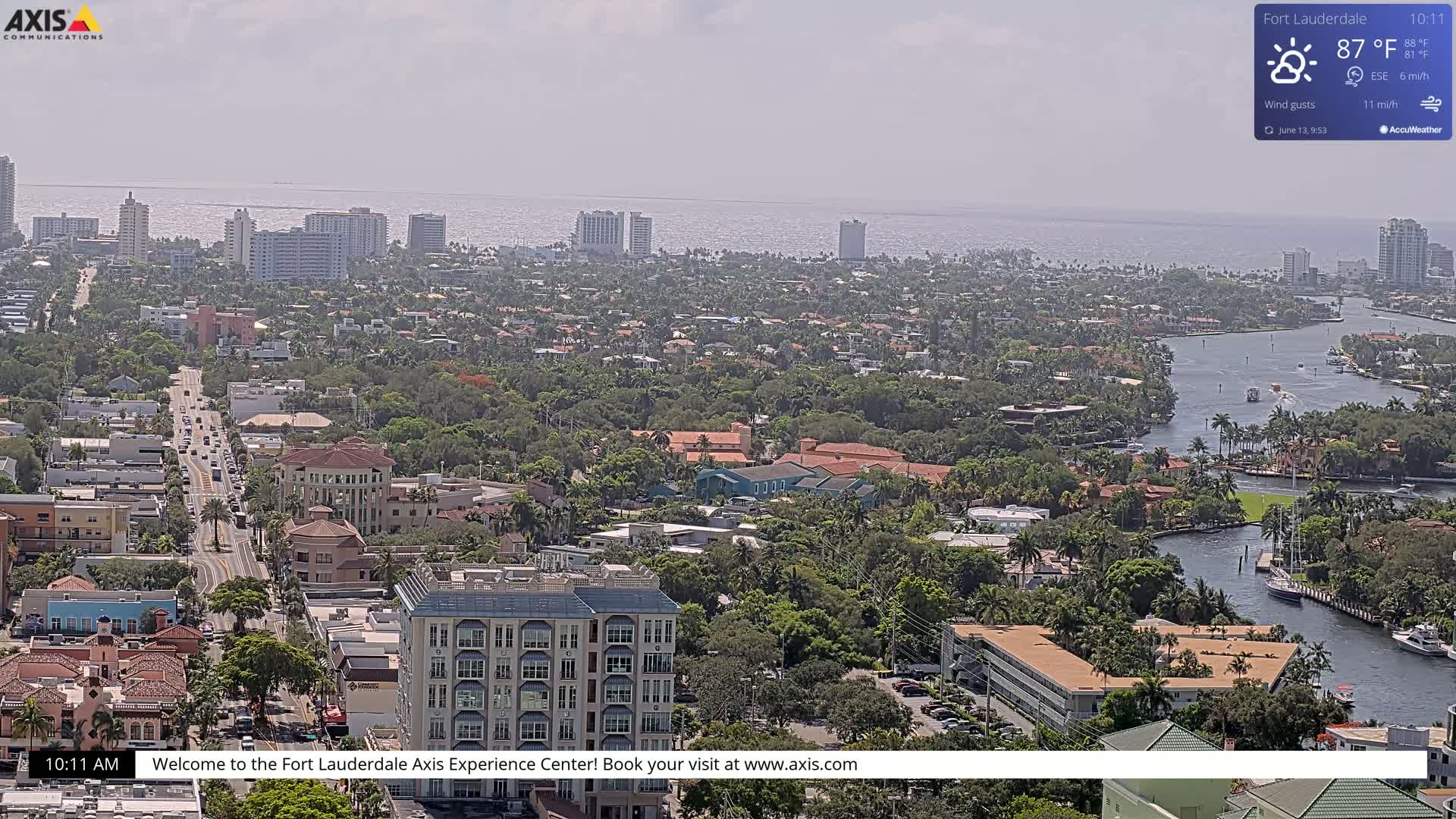 An aerial view shows a city with a waterway, under hazy sunny conditions.