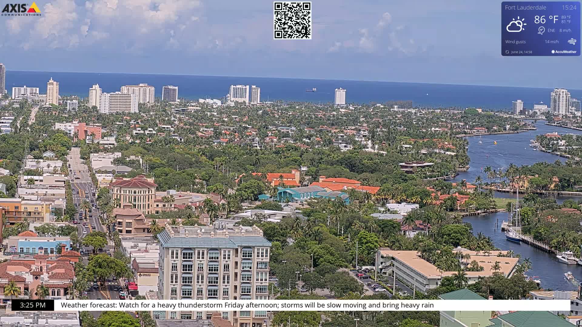 A coastal city with many buildings and palm trees, partially obscured by a waterway, is visible under partly cloudy skies.