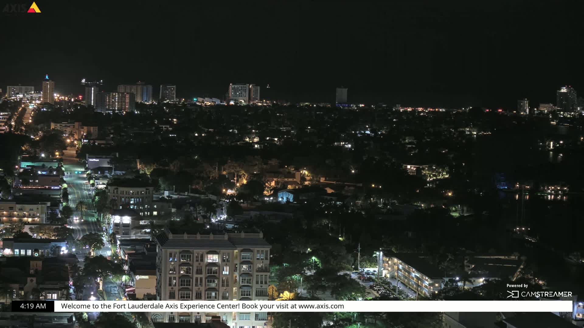 A nighttime aerial view of a city with numerous illuminated buildings and streets.