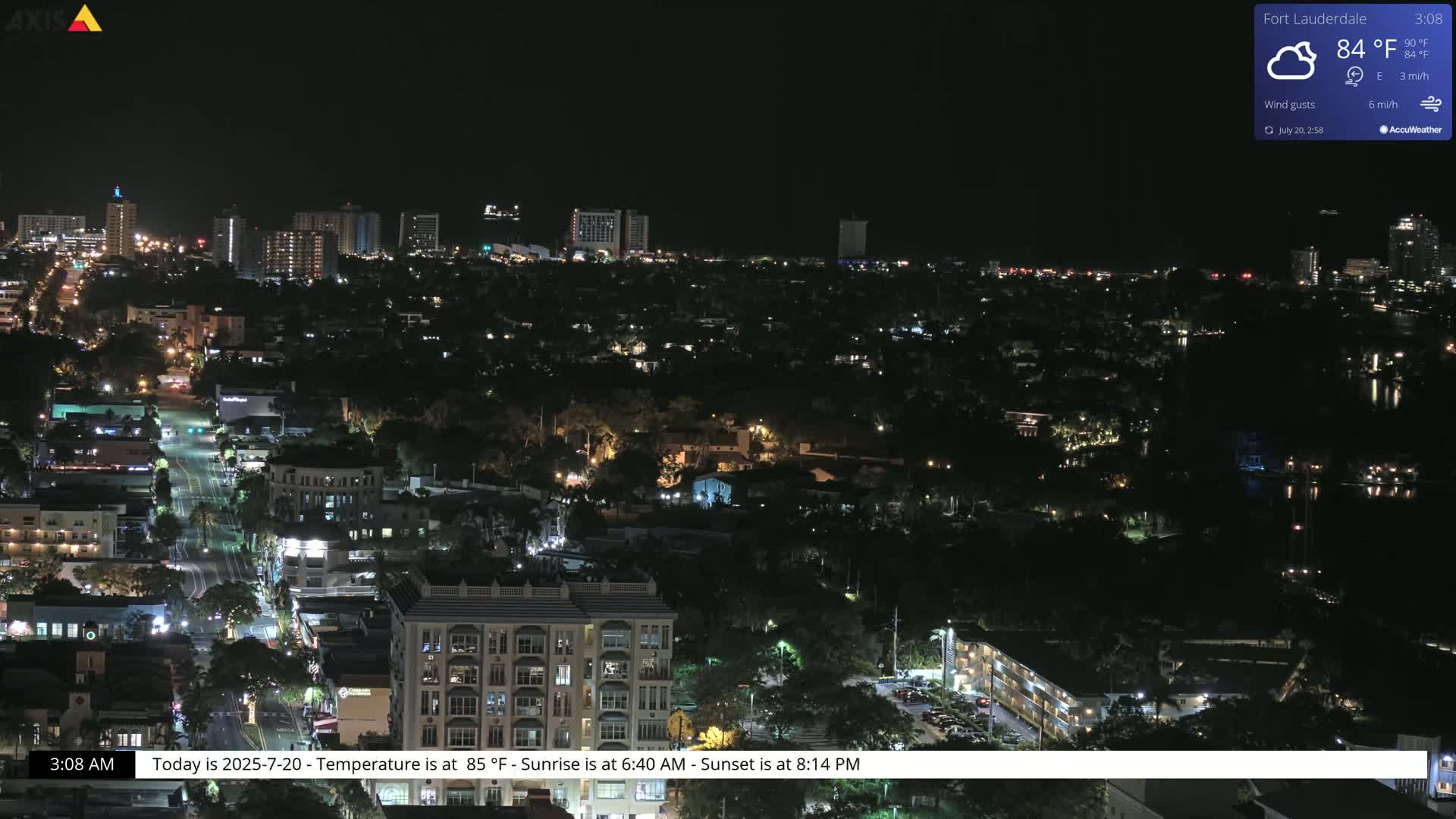 A nighttime aerial view of a city with scattered lights, under partly cloudy skies.