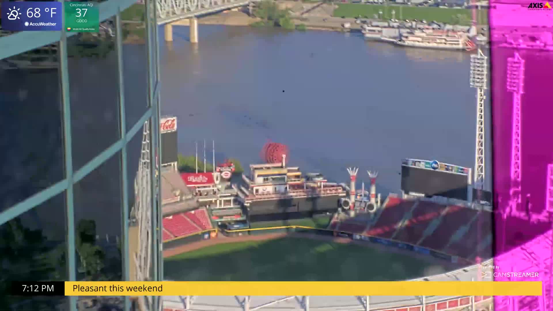A high-angle view shows a baseball stadium beside a river on a pleasant day.